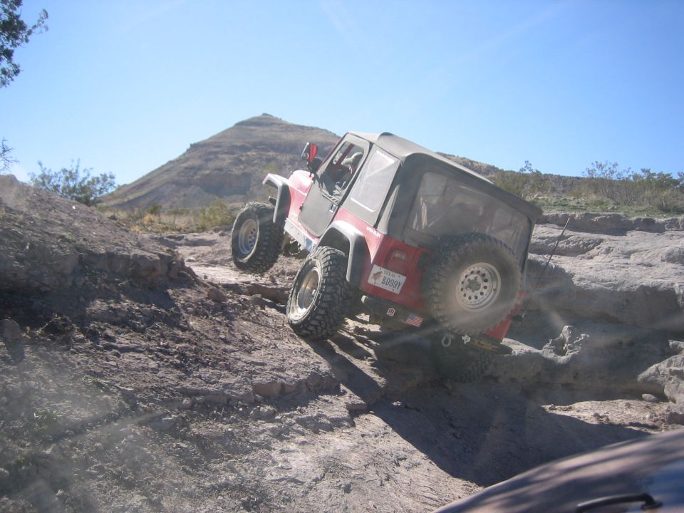 Red Jeep Wrangler climbing a rocky hill. License plate reads 'BOBBY'