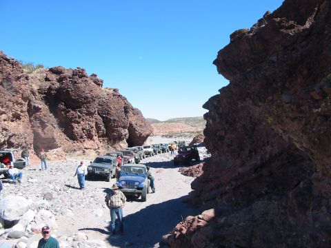 1996 Ford Bronco - A group of off-road vehicles navigate a rocky canyon under a clear blue sky.
