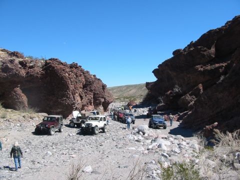 1996 Ford Bronco - A convoy of off-road vehicles navigates a rocky canyon under a clear blue sky.