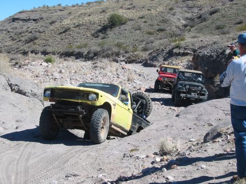 1996 Ford Bronco - Several off-road vehicles traverse a , mountainous terrain on a sunny day.