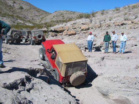 1996 Ford Bronco - A group of Jeeps tackle a challenging off-road course in a desert landscape.