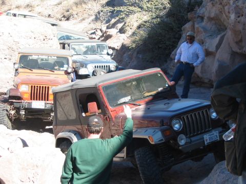 1996 Ford Bronco - A line of Jeeps navigates a rocky trail, with a red Wrangler in the foreground.