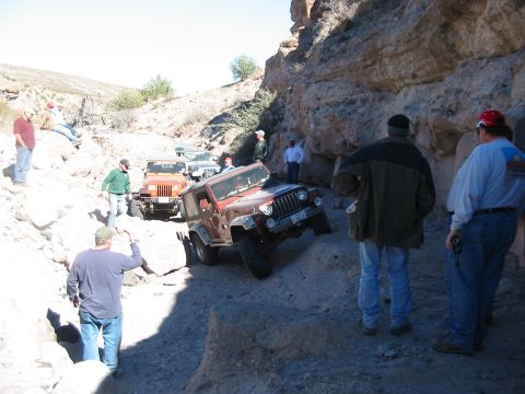 1996 Ford Bronco - A group of Jeeps navigates a challenging off-road trail through a canyon.