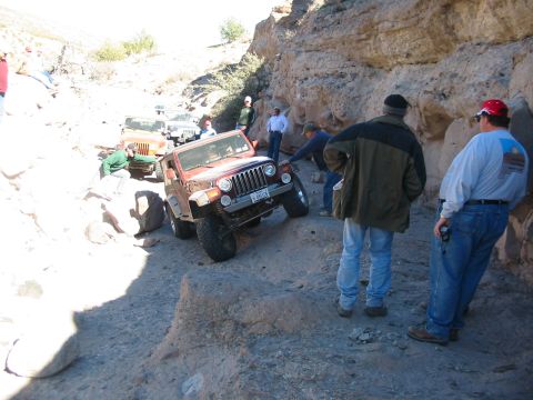1996 Ford Bronco - A convoy of Jeeps navigates a challenging off-road trail through a canyon.