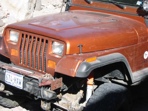 1996 Ford Bronco - Front view of an orange Jeep Wrangler, showing its grille, headlights, and fender with visible suspension components.