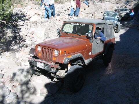 1996 Ford Bronco - Several Jeeps navigate a rocky trail with people watching.