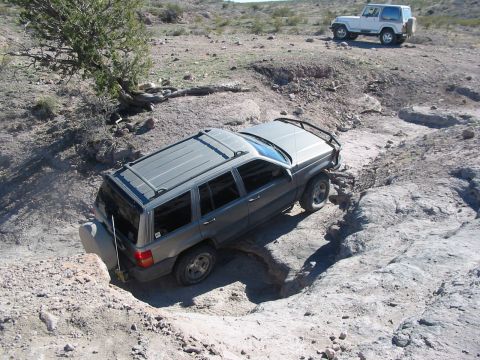 1996 Ford Bronco - Two Jeeps tackle a challenging off-road course in a desert landscape.