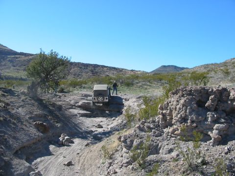 1996 Ford Bronco - A Jeep Wrangler navigates a challenging rocky terrain under a clear blue sky.