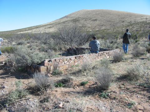 1996 Ford Bronco - A stone-lined structure sits in a dry, arid landscape with a hill in the background and several people present.