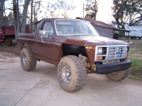 1981 Ford Bronco - This brown Ford Bronco features a lifted suspension and large off-road tires, with a grille that suggests an earlier model year.