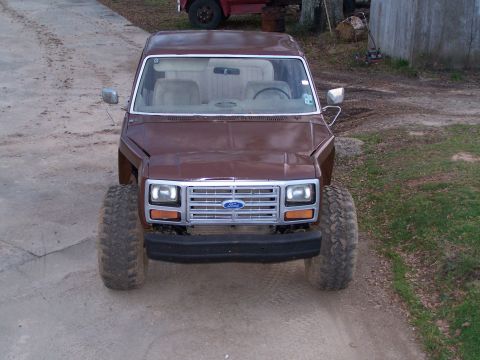 1981 Ford Bronco - This 1981 Ford Bronco features a prominent chrome grille and oversized tires, presented in a straightforward front-facing view.