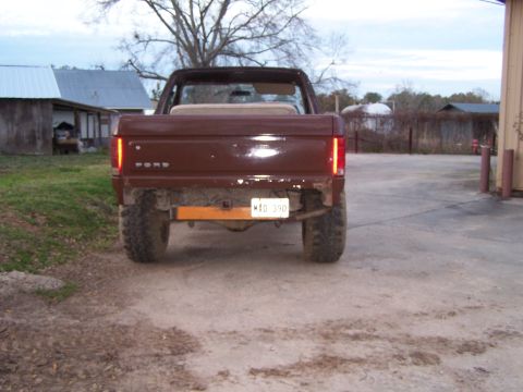 1981 Ford Bronco - Rear view of a lifted brown Ford Bronco with off-road tires and a custom bumper.