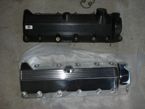1992 Ford Crown Victoria - Two valve covers are shown on a concrete surface. The top valve cover is black and appears to be made of plastic, while the bottom valve co…