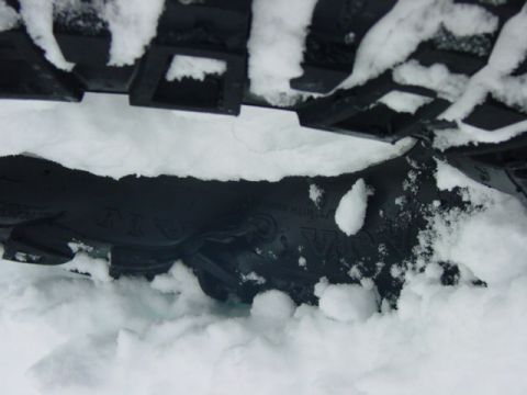 1986 Ford Bronco - A close-up view of a tire partially buried in snow, with the Supermotors logo visible in the lower right corner.