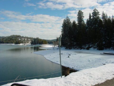 1986 Ford Bronco - A winter scene shows a snow-covered landscape next to a body of water with evergreen trees in the background.