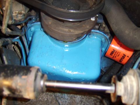 1989 Ford Bronco - Close-up of an engine bay showing a bright blue-painted engine block with a chrome-topped component above it and an orange FRAM oil filter…