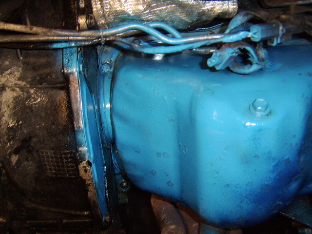 Blue oil pan viewed from underneath vehicle with fuel lines above