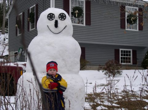 1996 Ford Probe - A child poses with a large snowman in a snowy yard, with a house in the background.