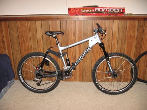 1997 Ford Probe - A silver Raleigh full-suspension mountain bike is shown indoors against a wood-paneled wall.