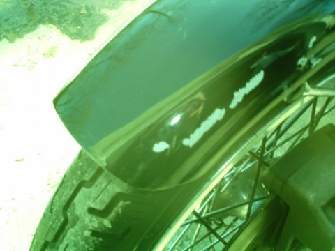 1979 Ford Bronco - Close-up of a motorcycle's fender and wheel, showing wear and tear.