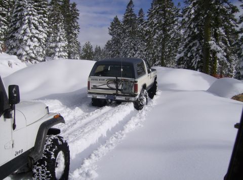 1986 Ford Bronco - A 1986 Ford Bronco navigates a snowy trail, followed by a Jeep in the foreground.