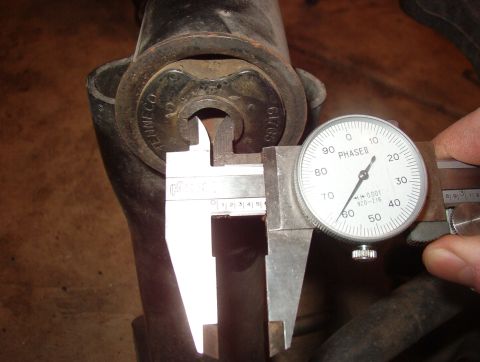 1993 Ford Bronco - Dial calipers are used to measure a metal part that has 'TENNECO' and '61/65' stamped on it.