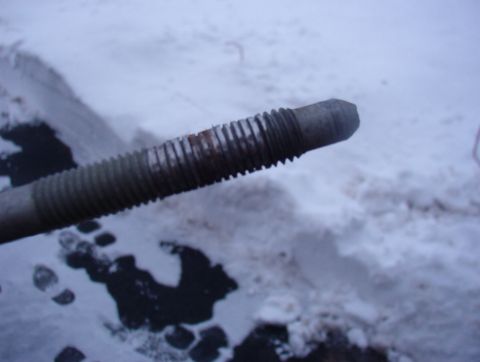 1993 Ford Bronco - A close-up shot of a threaded metal rod is shown against a snowy background with footprints.