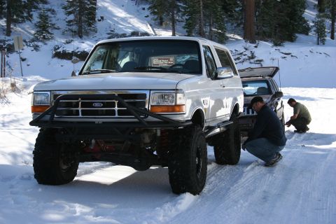 1996 Ford Bronco - A white 1996 Ford Bronco is modified for off-road use and parked in a snowy area with another vehicle behind it.