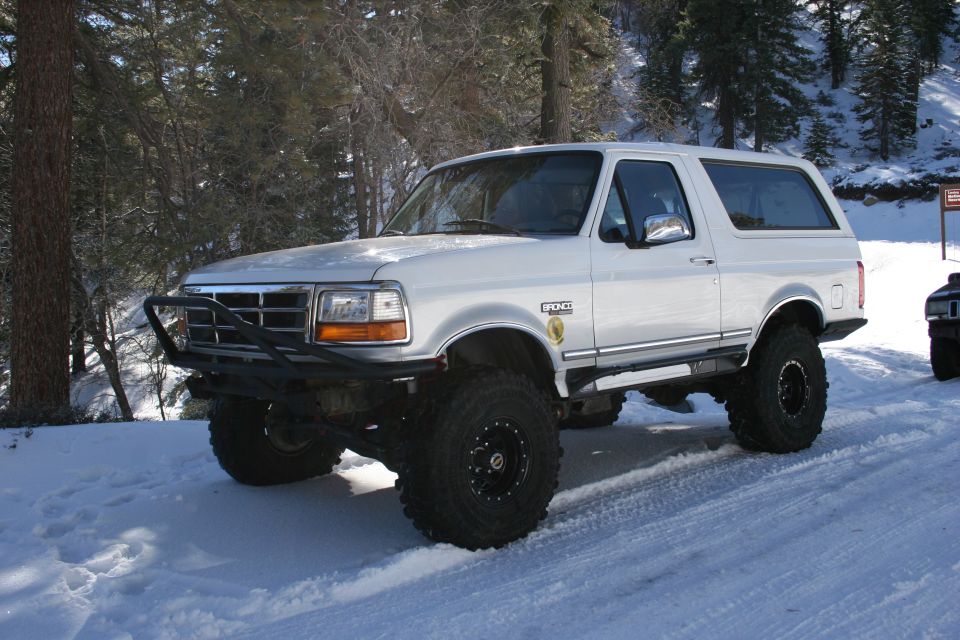 1996 Ford Bronco with aftermarket bumper and large tires parked in snow