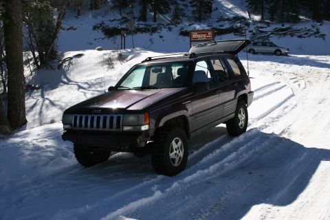 1996 Ford Bronco - A Jeep Grand Cherokee navigates a snow-covered road with a sign in the background.