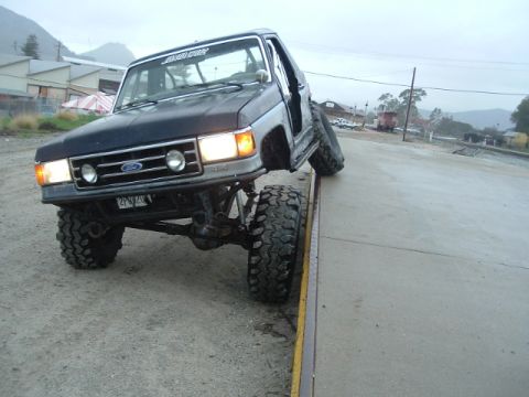 1989 Ford Bronco - This heavily modified Ford Bronco is shown with its front-left tire elevated, demonstrating its off-road capabilities.