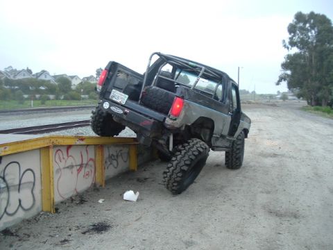 1989 Ford Bronco - Modified 1989 Ford Bronco is shown tilted on a barrier with large off-road tires.