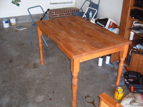 1988 Ford Bronco - A wooden dining table with turned legs sits on a concrete floor, surrounded by various items in what appears to be a garage or workshop.