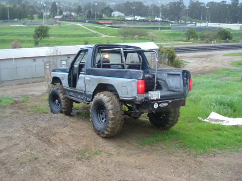 1989 Ford Bronco - This heavily modified SUV, likely from the 1980s, features oversized tires and a custom roll cage.