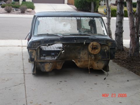 1978 Ford Bronco - Front end of a 1978 Ford Bronco, stripped down for parts or restoration. Text on windshield reads 'THIS ROLL ME OVER!'