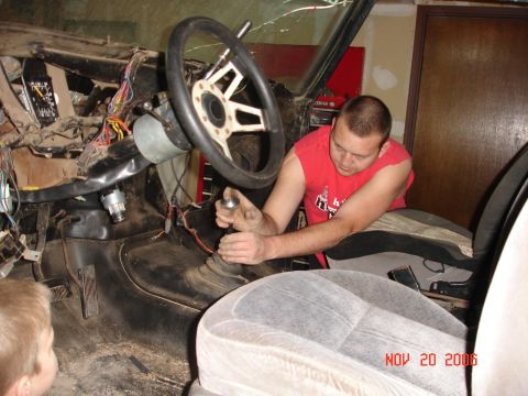 1978 Ford Bronco - A man works on the interior of a vehicle, with exposed wiring and dashboard components visible.