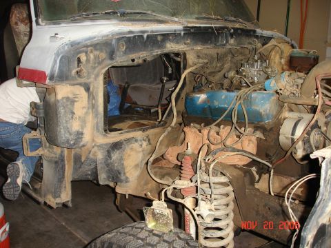 1978 Ford Bronco - The front end of a vehicle is disassembled, revealing the engine and suspension parts. A person is visible working on the left side.