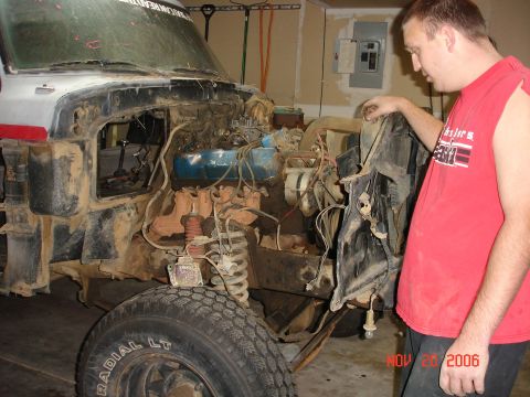 1978 Ford Bronco - A man inspects the engine bay of a 1978 Ford Bronco during a tear-down process.