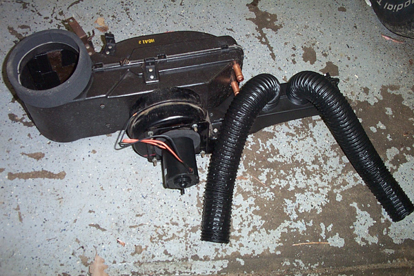 Heater core assembly with blower motor and flexible ducts on concrete floor