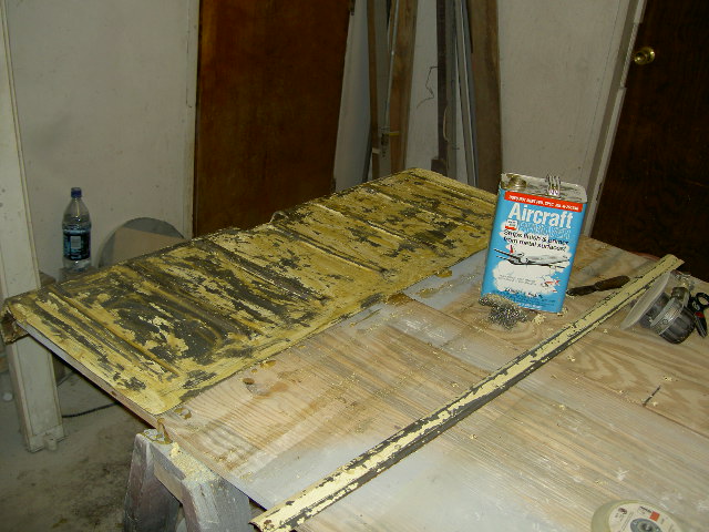 Peeling yellow paint on a car hood or trunk lid, with a can of Aircraft paint stripper