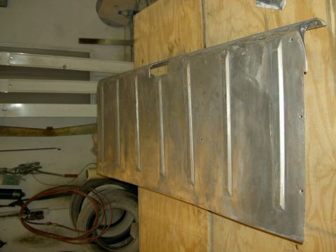 1967 Ford Ranchero - An aluminum tailgate with vertical ribs is mounted on a plywood surface in a workshop.