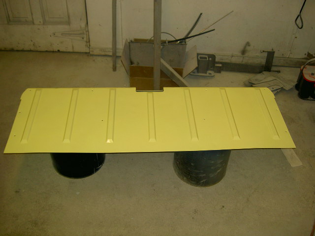 Yellow tailgate with vertical ribs, supported by two black barrels