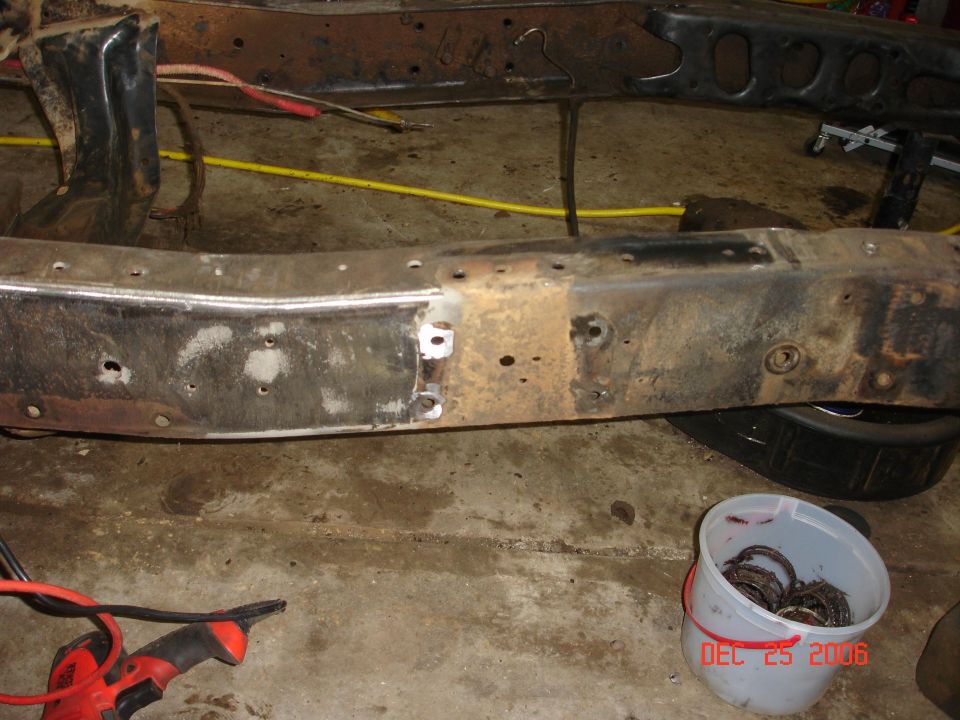 Vehicle frame with visible repair work and a bucket of parts