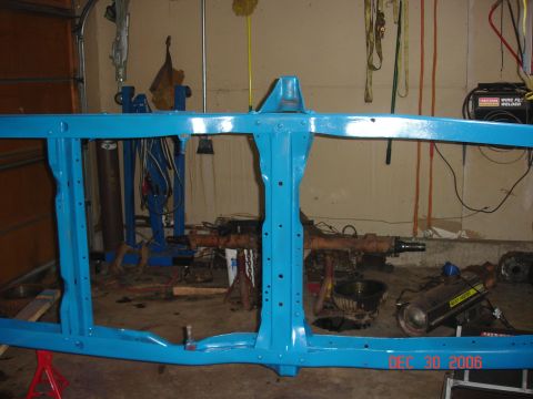 1978 Ford Bronco - A blue painted vehicle frame is shown in a garage setting, with various tools and parts in the background.