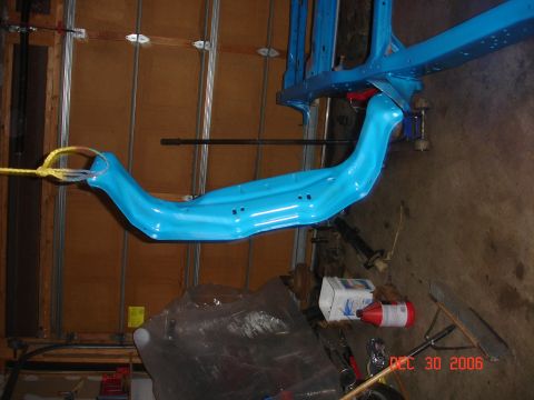 1978 Ford Bronco - A blue painted suspension component is suspended by a hoist during a frame build-up process.