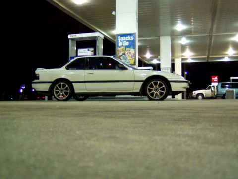 1993 Ford Probe - A white coupe is parked at a gas station under the lights at night, with other vehicles visible in the background.