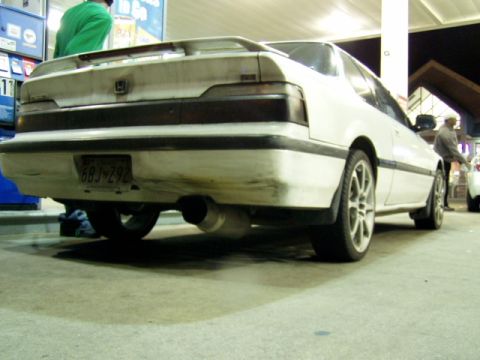 1993 Ford Probe - A white coupe with a spoiler and aftermarket exhaust sits at a gas station.