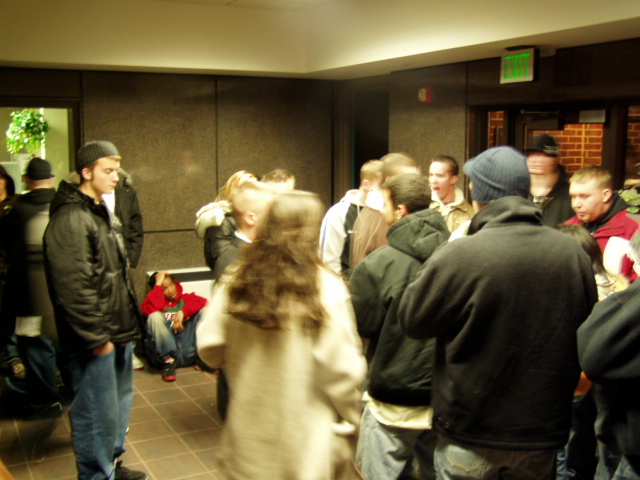 Group of people gathered indoors, some standing and some sitting
