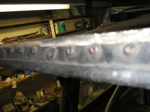 1966 Ford Bronco - A close-up view of a riveted metal edge, with a workshop environment visible in the background.