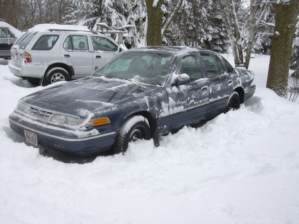 Dark blue 1996 Ford Crown Victoria stuck in deep snow, front 3/4 view